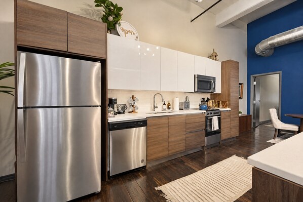 A modern kitchen with stainless steel appliances, wooden cabinets, and a blue accent wall.