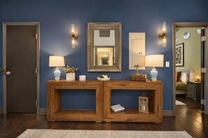 A wooden console table with two wall-mounted lamps, a mirror, and decorative items.