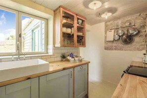 Eine Küche mit einem großen Fenster, Holzschränken und einer Steinwand mit Küchenutensilien.