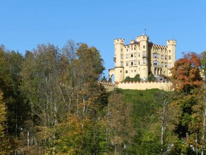 A castle-like building with multiple towers and a balcony, surrounded by dense forest. - Holiday Apartment With 1 Bedroom (Schwangau)