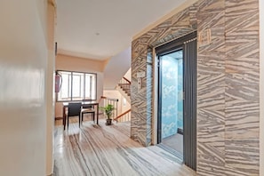 A hallway with a dining area, a staircase, and a door leading to a balcony. - GSILVER HOTEL HIMALAYA (Chennai)