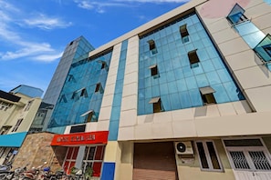 A modern building with a glass facade, a red sign indicating a hotel, and a closed shuttered entrance. - GSILVER HOTEL HIMALAYA (Chennai)
