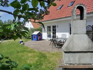 A house with a red-tiled roof, a small blue playhouse, a barbecue area, and a paved patio. - Holiday Home in Graal-muritz With Terrace (Graal Mueritz)