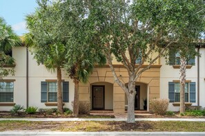A residential building with a symmetrical facade, a central entrance with a door, and a small porch area. - 5BR Townhome Steps from Clubhouse near Disney! (Kissimmee)