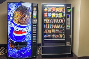 Two vending machines, one with a Pepsi advertisement and the other stocked with various snacks.