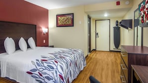 A hotel room with a large bed, a desk, a chair, a wardrobe, a door, and a wall-mounted TV. - BlissPoint Inn Perrysburg (Perrysburg)