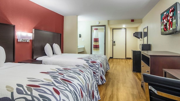 A hotel room with two beds, a desk, a television, and a door leading to a bathroom. - BlissPoint Inn Perrysburg (Perrysburg)