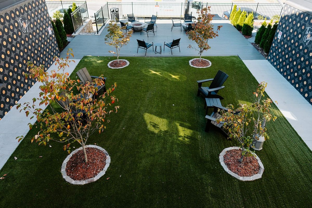 Un patio exterior con césped, zona de estar y macetas decorativas.