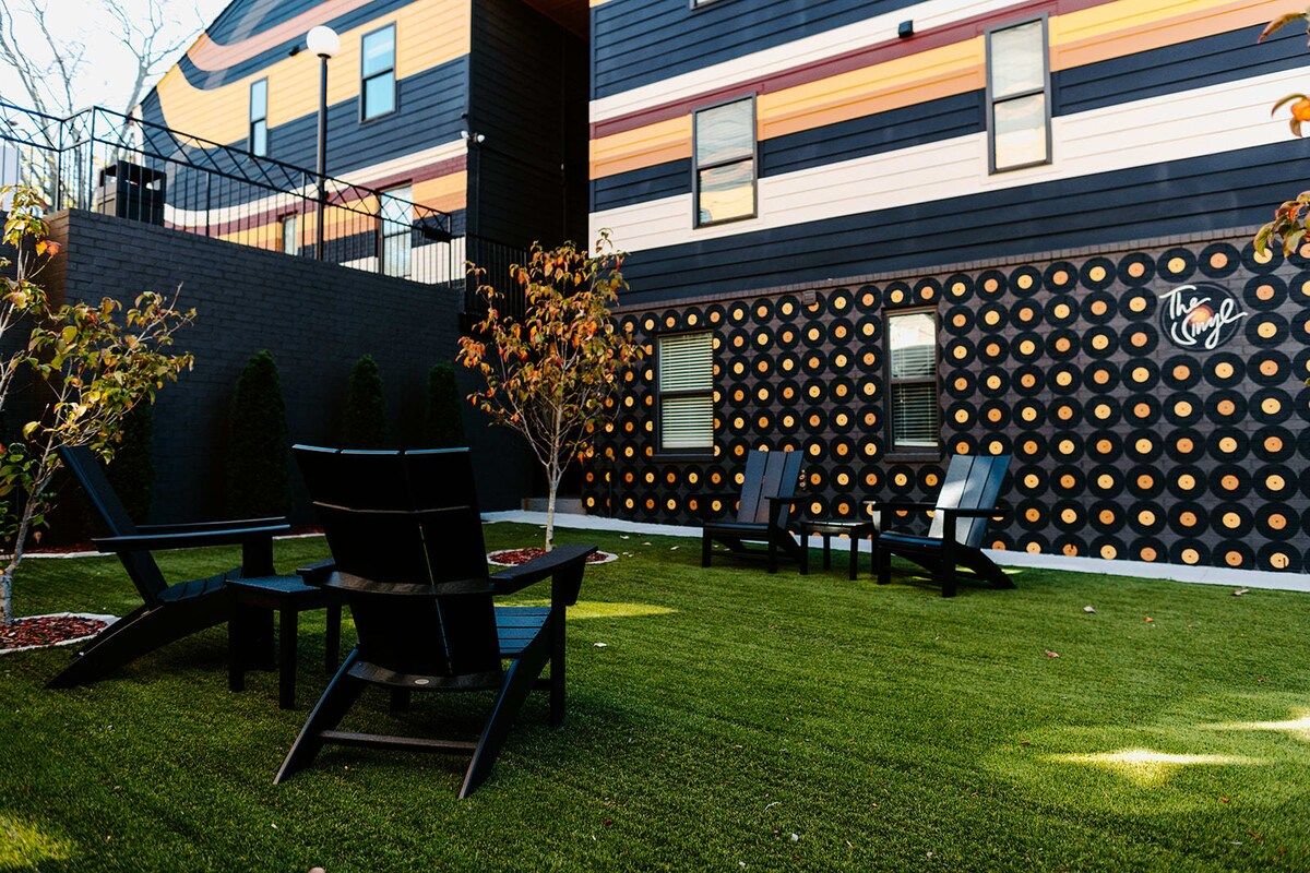 Un edificio moderno con un diseño único de pared de discos de vinilo, zona de estar al aire libre y un césped bien cuidado.