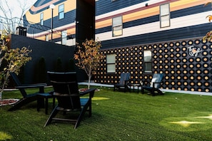 Un edificio moderno con un diseño único de pared de discos de vinilo, zona de estar al aire libre y un césped bien cuidado.