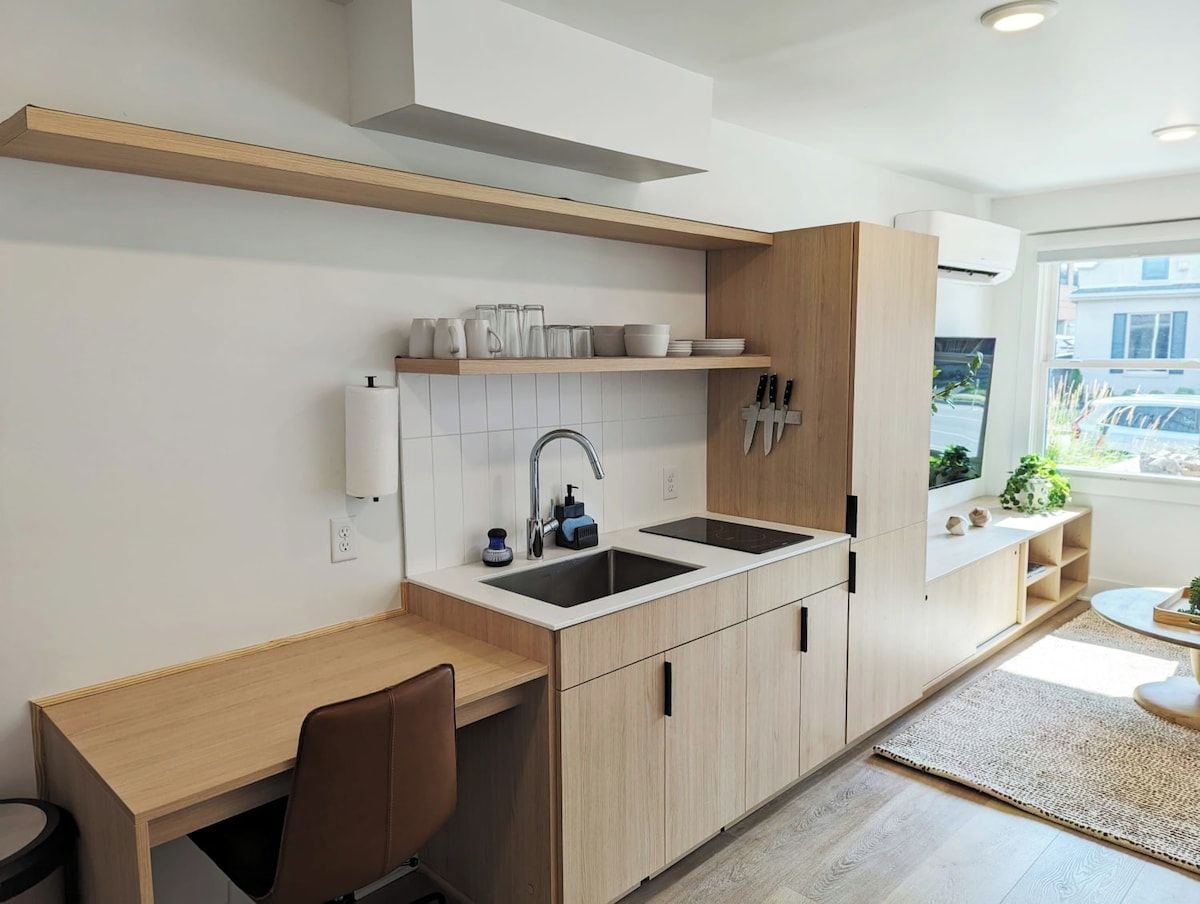 A modern kitchen with a wooden countertop, two sinks, and a window providing natural light.