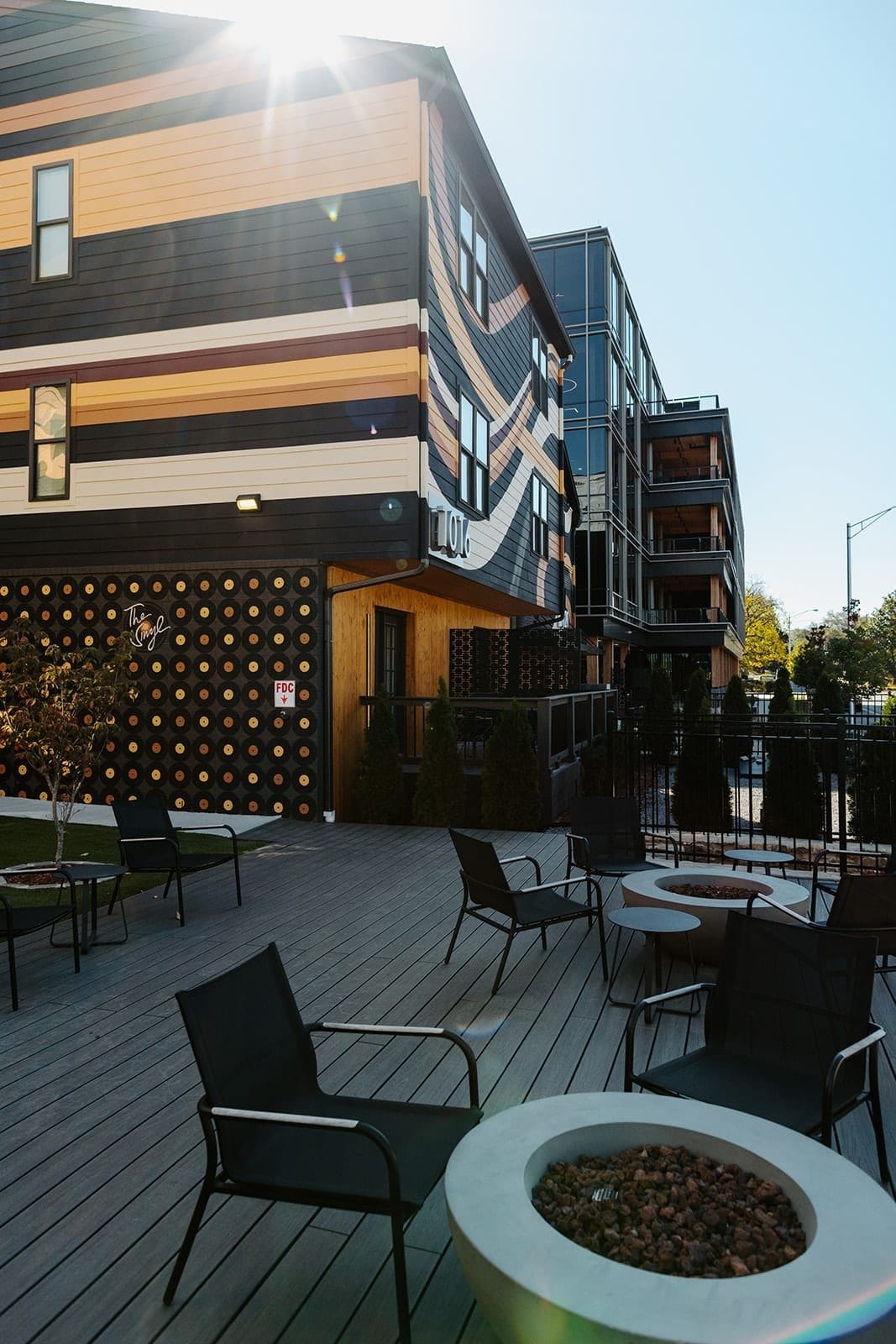 An outdoor seating area with modern furniture, a fire pit, and a building with a unique facade.