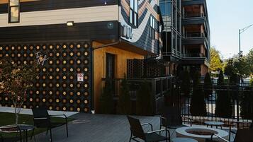 An outdoor seating area with modern furniture, a fire pit, and a building with a unique facade.