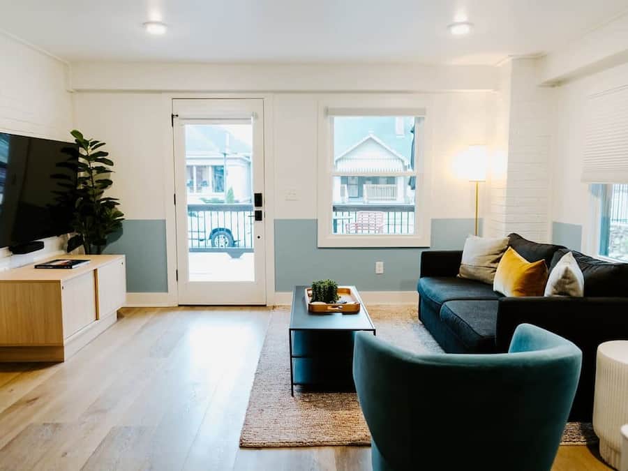 A modern living room with a flat-screen TV, a sofa, a coffee table, and a plant.