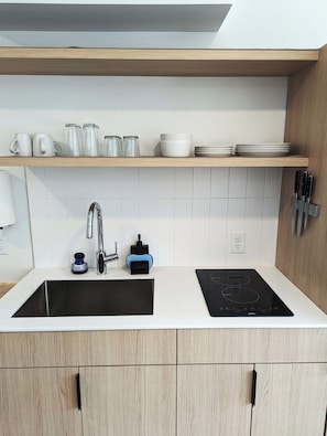 Una cocina moderna con un lavamanos doble, estufa integrada y un estante sobre el lavamanos con diversos utensilios de cocina.
