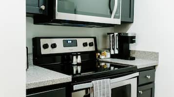 Cocina equipada con microondas, estufa, horno y armarios oscuros.