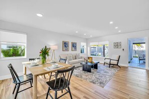 A modern living room with a dining area, featuring a sofa, chairs, a coffee table, and a view of the outdoors. - Beach Condo - Lush Patio - Birch 2 (Fort Lauderdale)