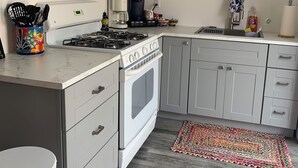 Een moderne keuken met een gasfornuis, oven, magnetron en koffiezetapparaat.