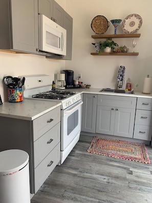 Et moderne køkken med gaskomfur, ovn, mikroovn og kaffemaskine.