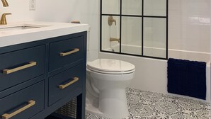 Een badkamer met een witte wastafel, een blauw aanrecht, een wit toilet, een douchecabine van glas en een blauwe handdoek.