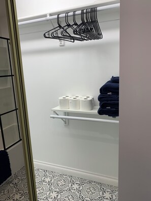 A closet with shelves holding towels and toilet paper.