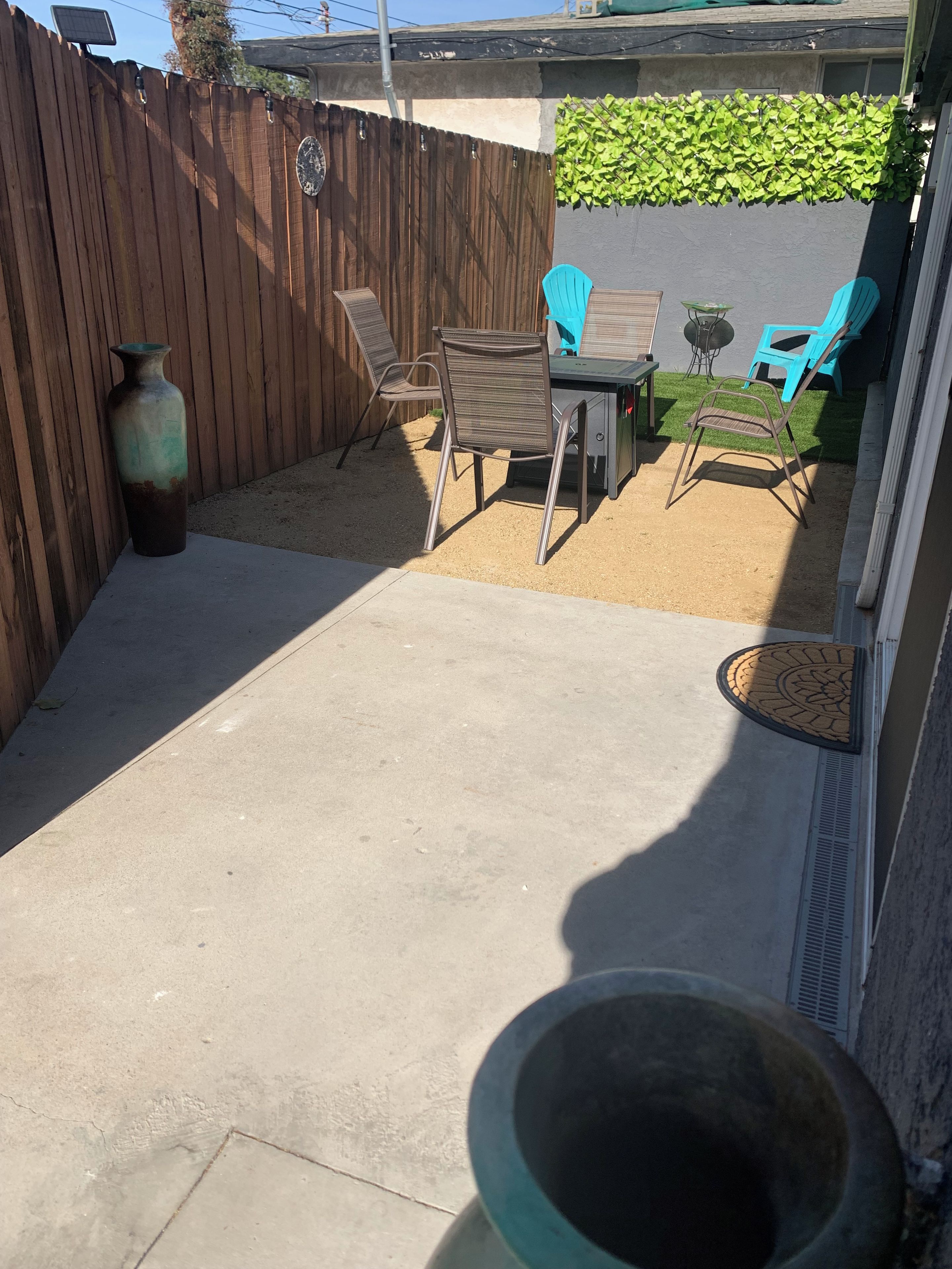 A patio area with a concrete floor, a wooden fence, and a table with chairs.