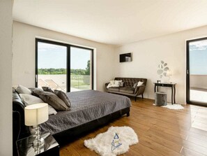 A bedroom with a large bed, a sofa, a small table, and a view through a sliding door. - Villa in Visnjan With Swimming Pool (Visnjan)
