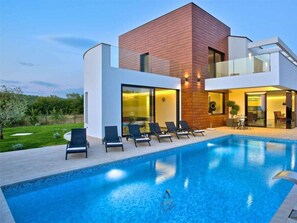 A modern house with a swimming pool, lounge chairs, and a well-maintained garden. - Villa in Visnjan With Swimming Pool (Visnjan)