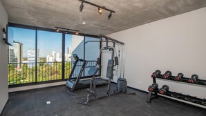 Un gimnasio con equipo de ejercicio, cinta de correr y mancuernas.