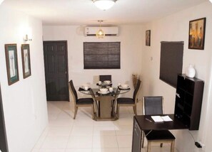A dining area with a round table, chairs, and a black cabinet. - Cozy 2 bedroom house in Trincity (Trincity)