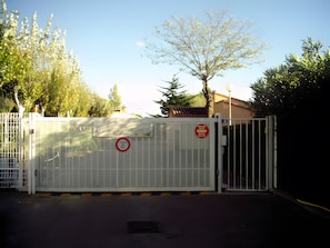 Una entrada con puerta metálica y un letrero que dice 'Los Aigues Martinas', junto a una señal de 'prohibido el paso'.