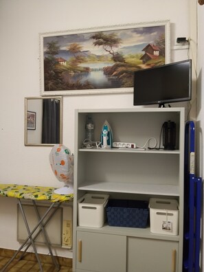 A room with a painting, a television, an ironing board, and storage shelves. - Villa Bord De Mer* chez roselyne* shops and beach on foot* private garden, parking, Wi-Fi (Saint-Cyprien)