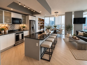 A modern kitchen with a central island, stainless steel appliances, and a dining area with a view of the city. - 3BR Edgewater High Rise Bay & Skyline Views (Miami)