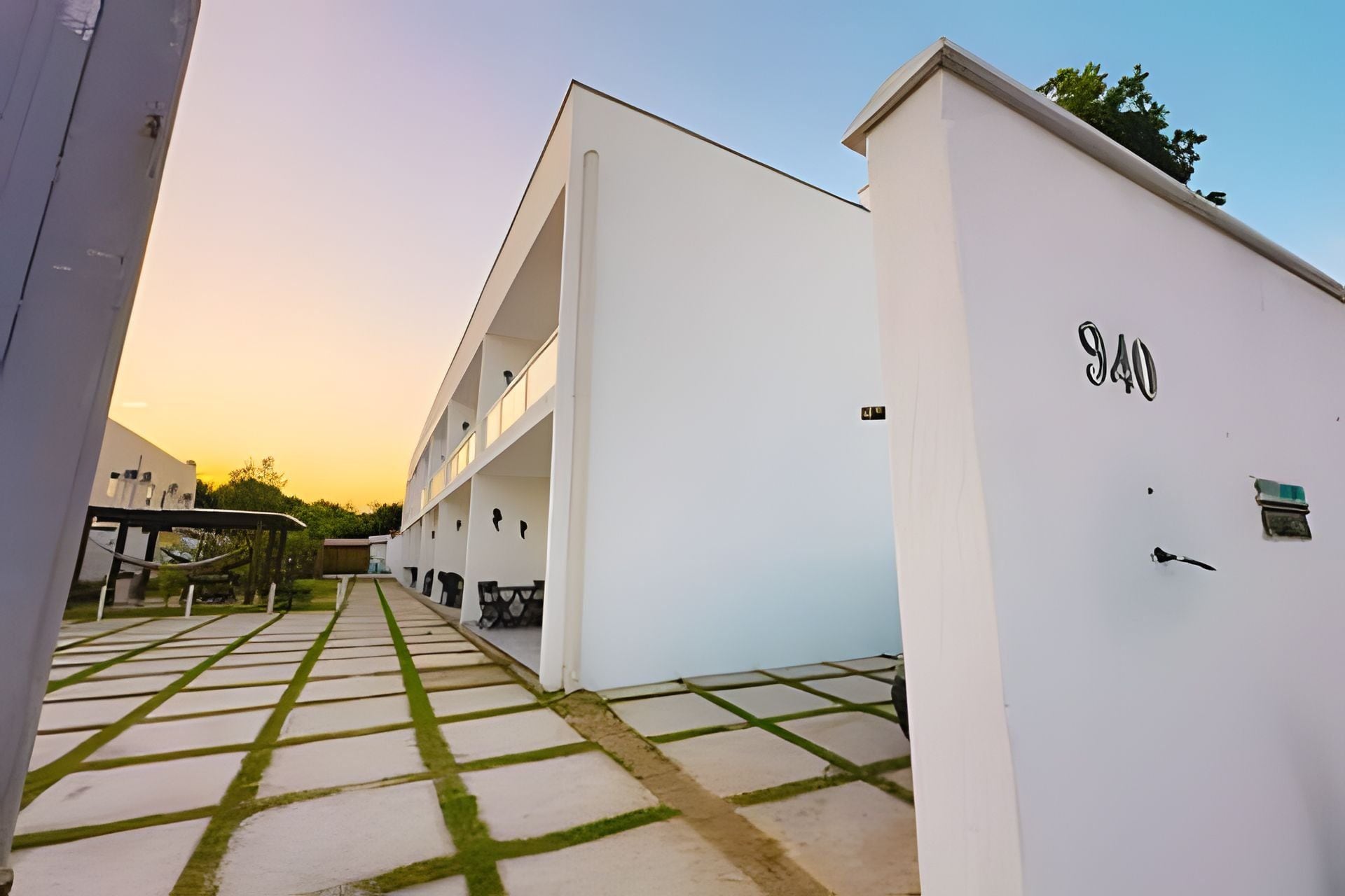 A modern building with a flat roof, a visible number '940' on the side, and a paved pathway leading to the entrance.
