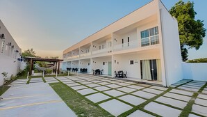 Un edificio moderno de varios pisos con techo plano, amplias ventanas y una zona de estar cubierta al aire libre.