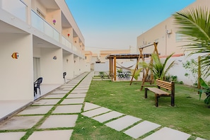 A courtyard with a swing set, a bench, and a hammock. - Apartamento 3 com 2 suítes 450m da praia (Santa Cruz Cabrália)