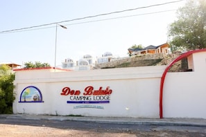 A white wall with the text 'Don Bullo Camping Lodge' and a small graphic of a beach scene.