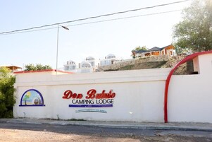 A white wall with the text 'Don Bullo Camping Lodge' and a small graphic of a beach scene.