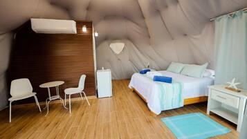 Een slaapkamer met een bed, nachtkastje en een stoel.