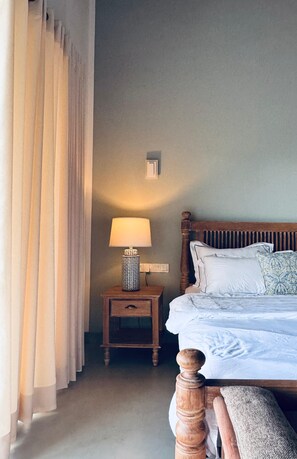 A hotel room with a bed, a nightstand with a lamp, and a window with curtains.