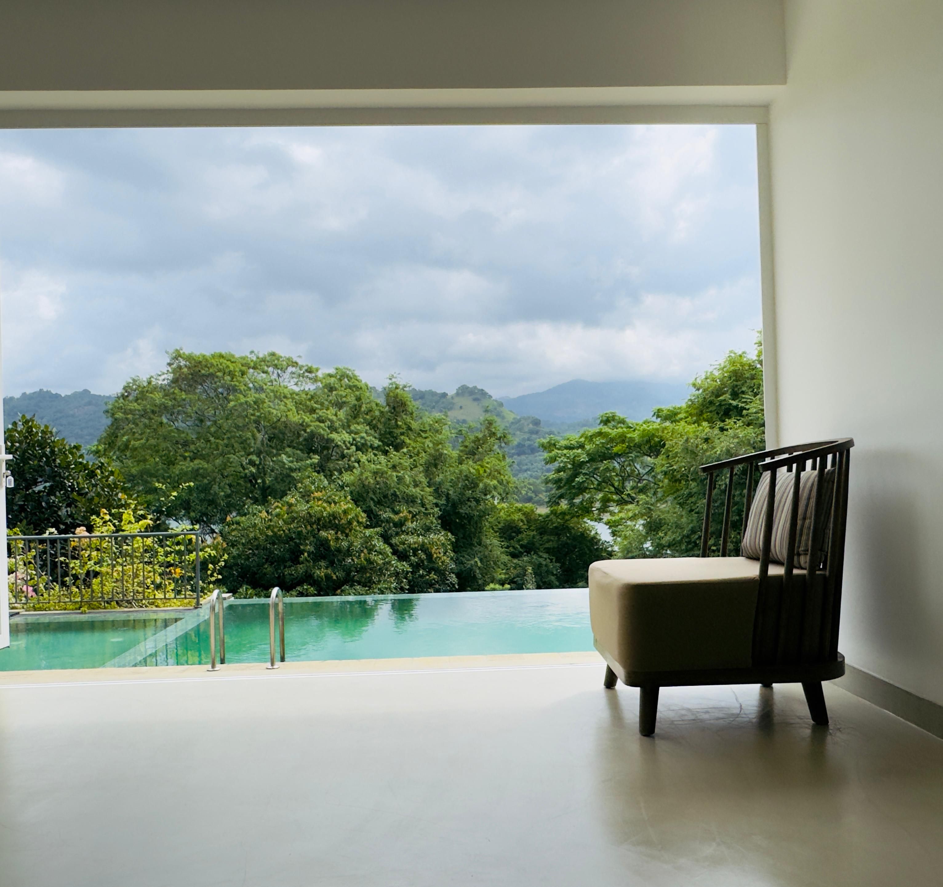 Ein Zimmer mit Blick auf einen Pool und üppige Grünanlage.