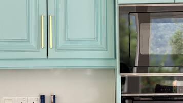 A kitchen with teal cabinets, gold handles, and a stainless steel oven.