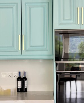 A kitchen with teal cabinets, gold handles, and a stainless steel oven. - Villa Eranya Kandy (Digana)