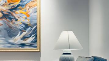 Ein Wohnzimmer mit einer Couch, einer Lampe und einem Gemälde an der Wand.