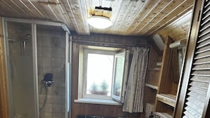 A compact bathroom with a shower, toilet, and sink, featuring wooden walls and a window. - Hex"nhausla in Aufsess (Aufsess)