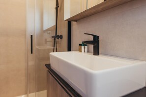 A bathroom with a white sink, black faucet, and a shower area with a glass door. - Luxury Forest Retreat With Pool Access (Karlovac)