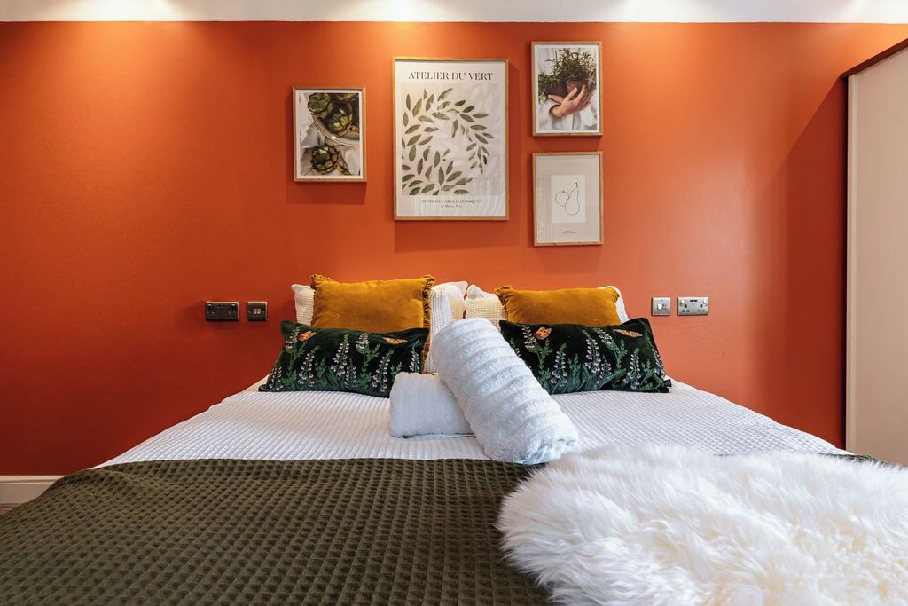 A hotel room with a bed, pillows, a blanket, and wall art.