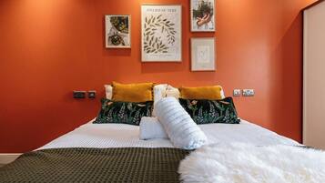 A hotel room with a bed, pillows, a blanket, and wall art.