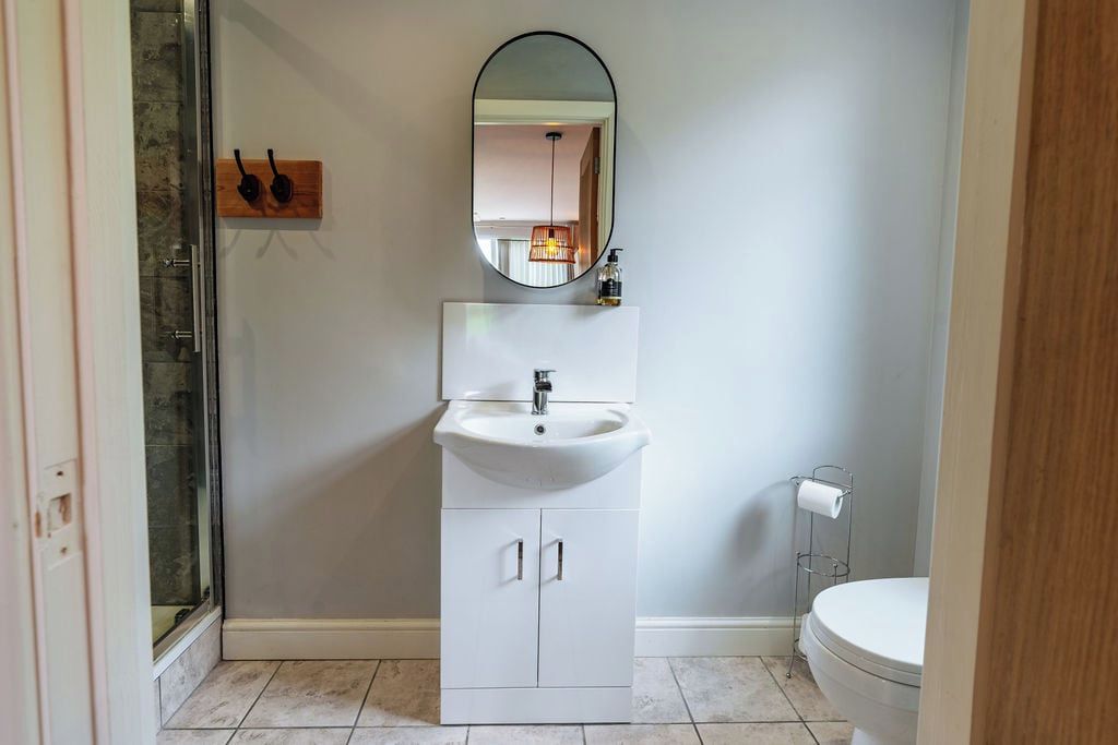 Un baño con lavamanos, espejo e inodoro blancos.