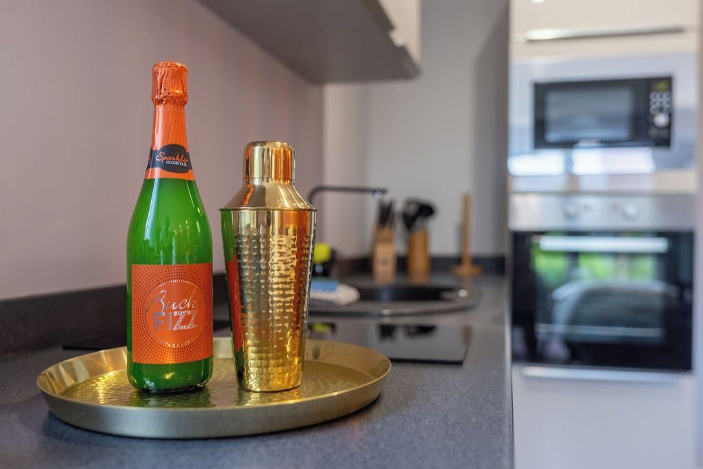 A kitchen counter with a bottle of Sparkling Cocktail and a cocktail shaker on a tray.